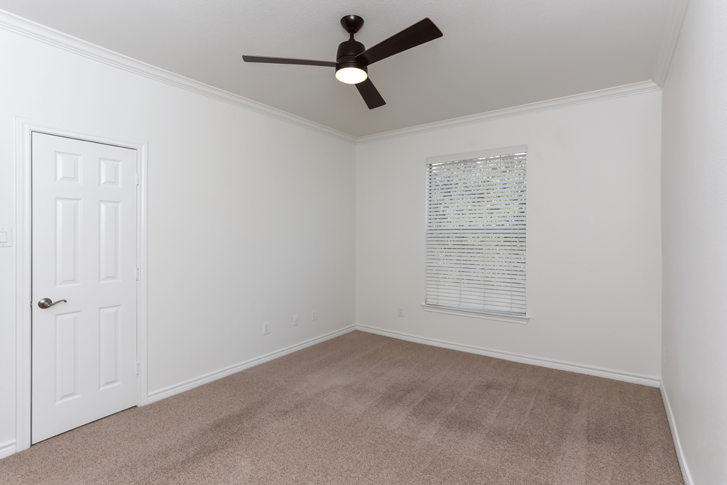 A room with a ceiling fan and a door.
